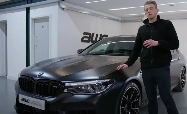 Man standing beside a black BMW car, discussing the cost of wrapping