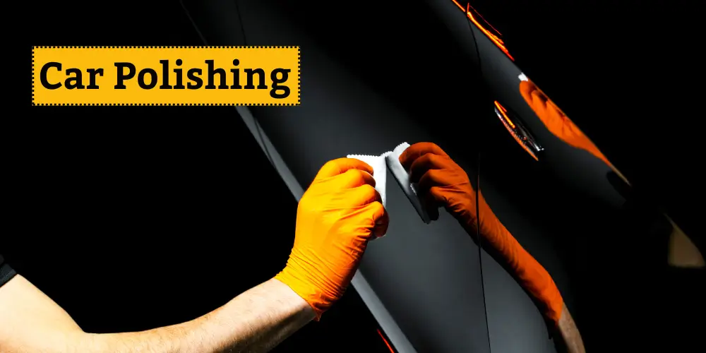 Person polishing a car's surface with an orange glove, creating a smooth and reflective finish.