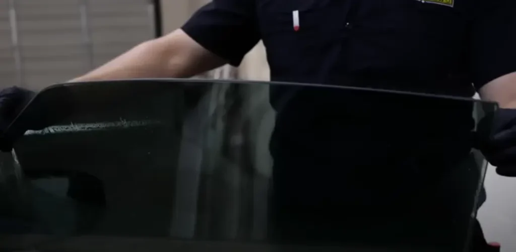 Technician carefully cleans a tinted car window, showcasing the precision and expertise involved in the window cleaning process.