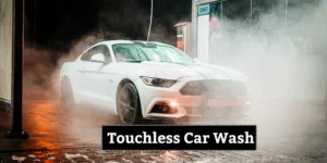 A white sports car undergoing a touchless car wash, surrounded by high-pressure water jets and mist.