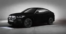 A sleek black luxury BMW with glowing red taillights, parked in a dimly lit modern setting