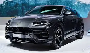 A luxurious black Lamborghini SUV with a sharp, aggressive front design and sleek contours, displayed in a modern showroom setting.