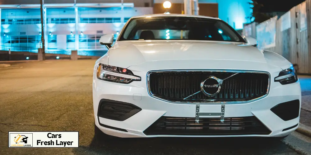 A stunning white Volvo parked under city lights, showcasing its luxury design and bold grille.