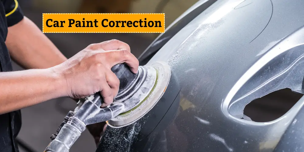 A person using a polishing machine on a car panel as part of a car paint correction process