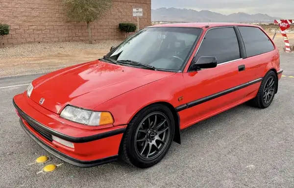 4th-generation Honda Civic hatchback in red, featuring classic styling and sporty black alloy wheels, parked on a quiet street