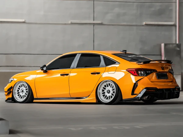 A customized 11th-generation Honda Civic wrapped in a stunning gloss metallic yellow finish, parked in a modern garage